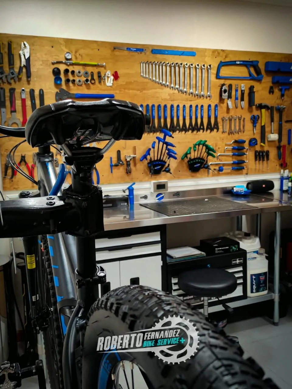 Bicicleta montada en el pedestal de trabajo frente al panel de herramientas del taller
